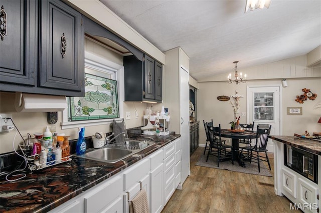 2 S Circle Dr, Carlyle, IL 62231 - kitchen with dark countertops, black microwave, lofted ceiling, a chandelier, and light wood-type flooring