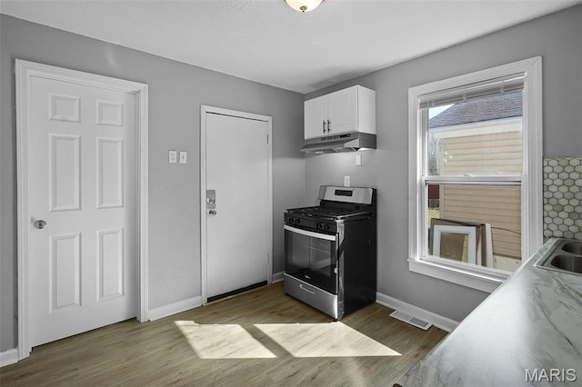 2430 Wallis Ave, Saint Louis, MO 63114 - kitchen with stainless steel gas range, dark wood-type flooring, white cabinets, and baseboards