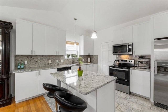 9 Amber Ridge Ct, High Ridge, MO 63049 - kitchen with stainless steel appliances, backsplash, vaulted ceiling, a breakfast bar, and white cabinets