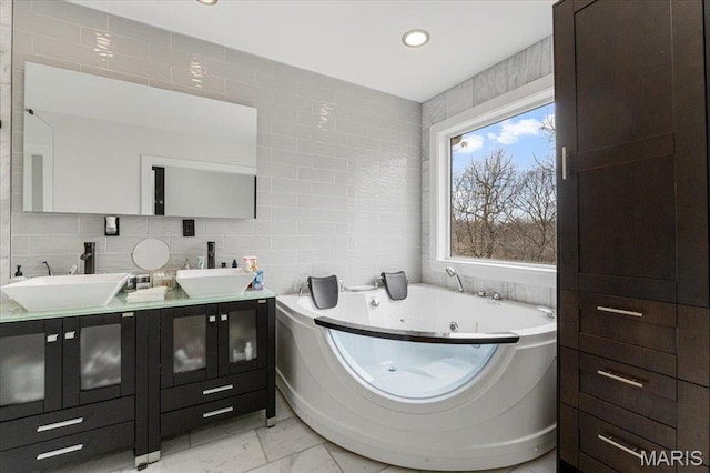 9 Amber Ridge Ct, High Ridge, MO 63049 - bathroom with tile walls, marble look tiles, double vanity, a jetted tub, and recessed lighting