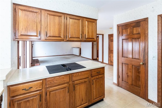 14 Webster Oaks Dr, Webster Groves, MO 63119 - kitchen featuring black electric stovetop, wallpapered walls, brown cabinetry, and light countertops