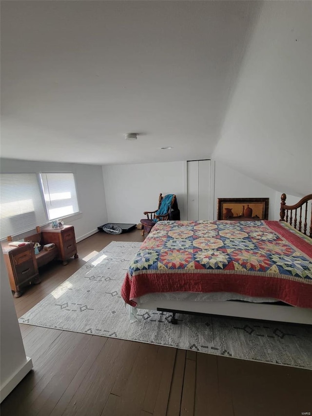 bedroom with wood finished floors and lofted ceiling