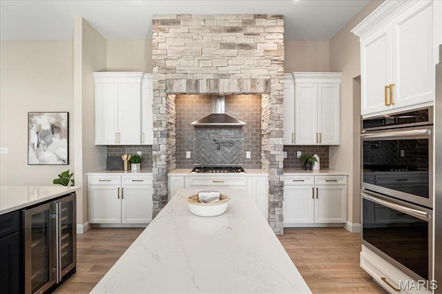 504 Coppice Ct, Wentzville, MO 63385 - kitchen featuring appliances with stainless steel finishes, wine cooler, wall chimney exhaust hood, and white cabinets