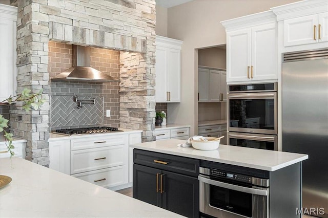 504 Coppice Ct, Wentzville, MO 63385 - kitchen with stainless steel appliances, wall chimney range hood, decorative backsplash, white cabinetry, and light stone countertops