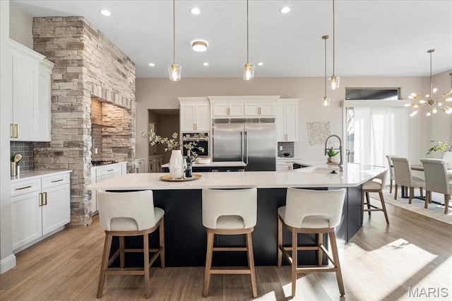 504 Coppice Ct, Wentzville, MO 63385 - kitchen featuring stainless steel appliances, a sink, light wood-style flooring, a large island, and a chandelier