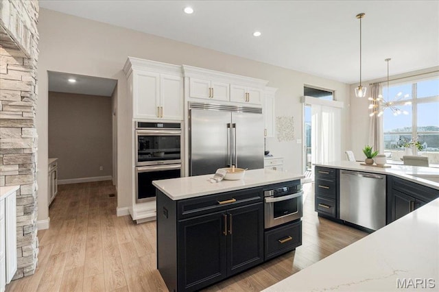 504 Coppice Ct, Wentzville, MO 63385 - kitchen featuring stainless steel appliances, dark cabinets, white cabinetry, a chandelier, and decorative light fixtures