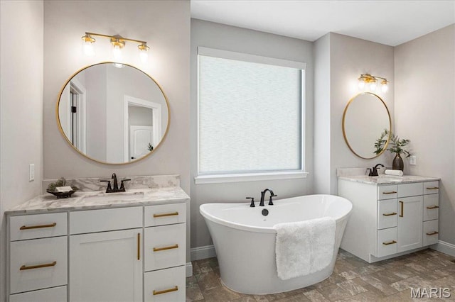 504 Coppice Ct, Wentzville, MO 63385 - bathroom with baseboards, stone finish flooring, a freestanding bath, and two vanities