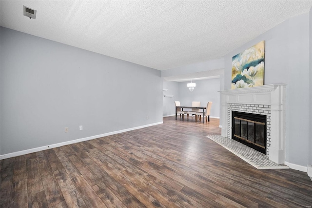 1593 Thrush Ter, Brentwood, MO 63144 - unfurnished living room with wood finished floors, a textured ceiling, a chandelier, baseboards, and a brick fireplace