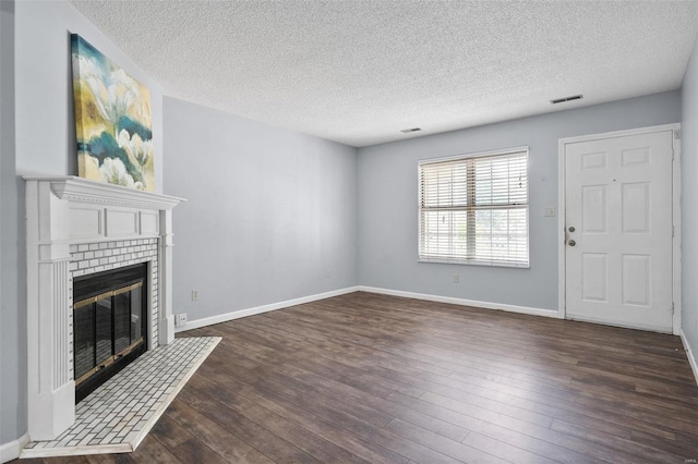 1593 Thrush Ter, Brentwood, MO 63144 - unfurnished living room featuring a textured ceiling, dark wood-style floors, a tiled fireplace, and baseboards