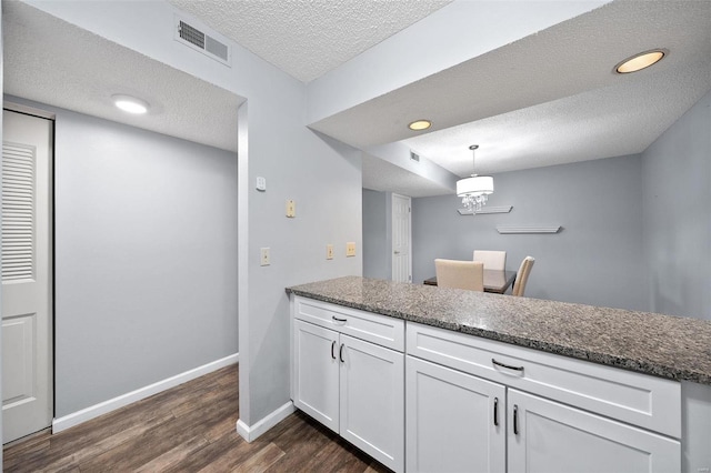 1593 Thrush Ter, Brentwood, MO 63144 - kitchen featuring white cabinetry, dark wood-style flooring, a textured ceiling, baseboards, and a peninsula