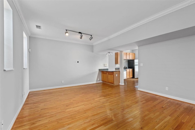 unfurnished living room featuring rail lighting, crown molding, light wood finished floors, and baseboards