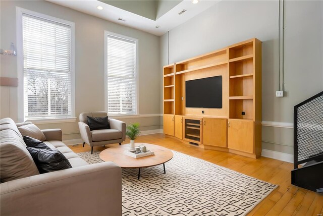 living room with light wood finished floors, plenty of natural light, baseboards, beverage cooler, and recessed lighting