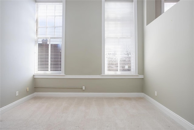 carpeted empty room featuring baseboards