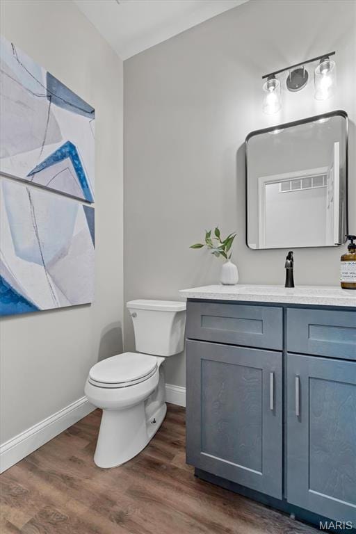 bathroom with toilet, baseboards, vanity, and wood finished floors