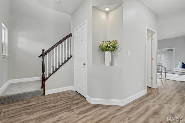 entryway with wood finished floors, baseboards, and stairway