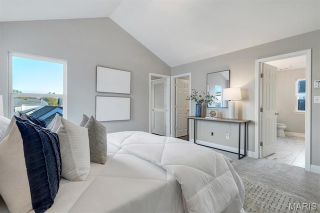 bedroom with lofted ceiling, multiple windows, ensuite bath, and baseboards