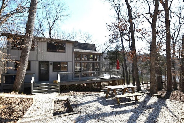 back of property with a wooden deck and a sunroom
