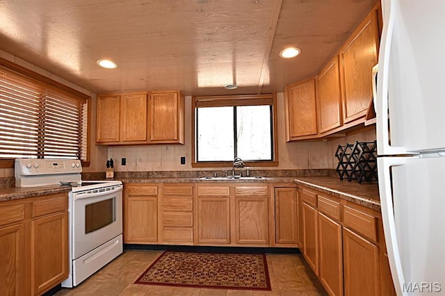 kitchen with white appliances, a sink, recessed lighting, and dark countertops