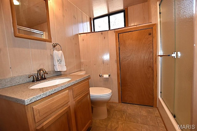 bathroom featuring wooden walls, toilet, and vanity