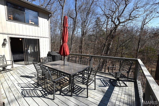 wooden terrace with outdoor dining space and a grill