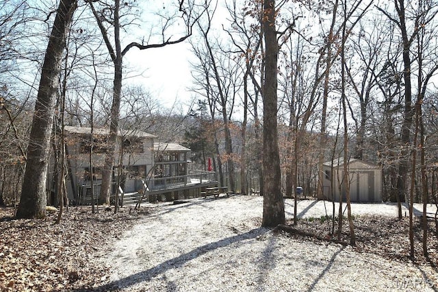 view of yard with a wooden deck, a storage shed, and an outbuilding