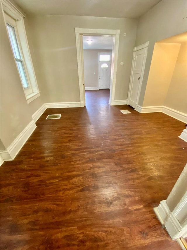 unfurnished room featuring dark wood-style flooring, baseboards, and healthy amount of natural light