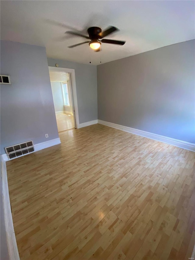 spare room with light wood-type flooring, ceiling fan, and baseboards