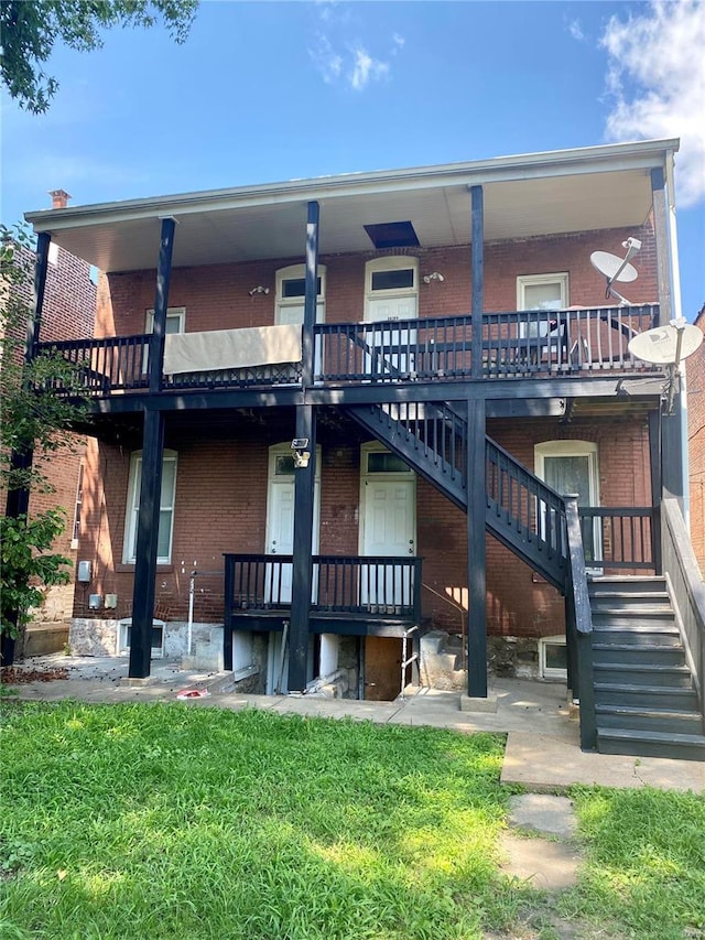 back of property featuring brick siding, stairs, and a lawn