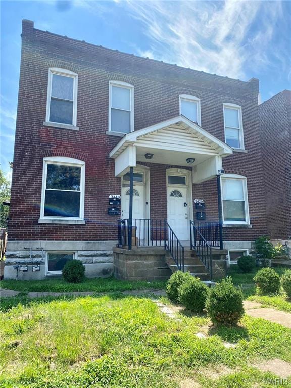 multi unit property featuring brick siding and a front yard