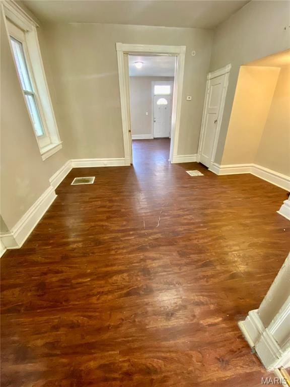spare room featuring dark wood-type flooring, healthy amount of natural light, and baseboards