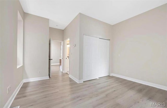 unfurnished bedroom featuring wood finished floors, baseboards, and a closet