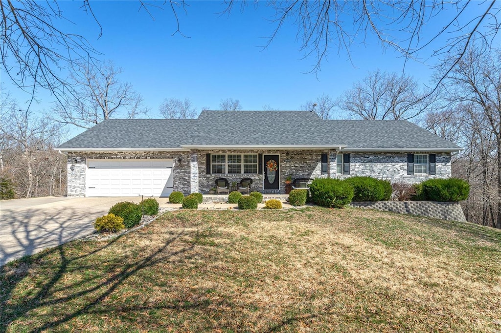 view of front of property featuring a porch, a garage, a front yard, concrete driveway, and roof with shingles