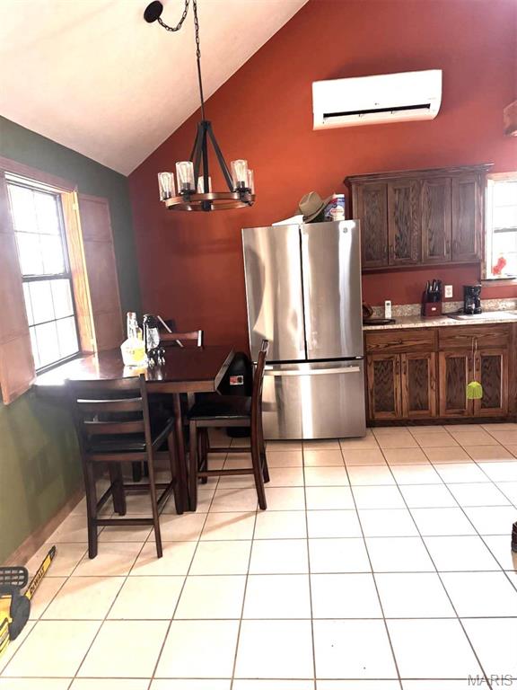 27409 Missouri Dr, Lebanon, MO 65536 - kitchen featuring freestanding refrigerator, a wall mounted air conditioner, lofted ceiling, light tile patterned floors, and a chandelier