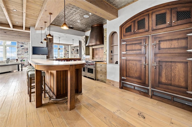150 Carondelet Unit 2901, Saint Louis, MO 63105 - kitchen with double oven range, wall chimney exhaust hood, light wood-type flooring, a breakfast bar area, and light countertops