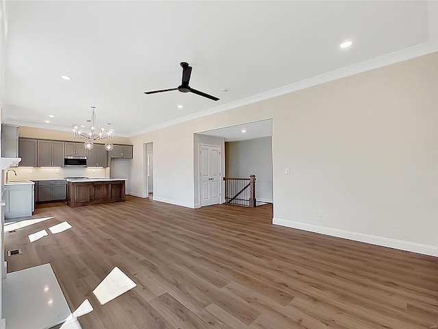 220 Great Bear Pass, Foristell, MO 63348 - unfurnished living room featuring crown molding, a sink, a chandelier, wood finished floors, and baseboards