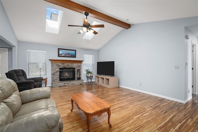 living area featuring wood finished floors, a ceiling fan, baseboards, a fireplace, and a skylight