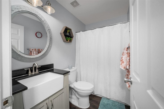bathroom featuring toilet, vanity, wood finished floors, and curtained shower