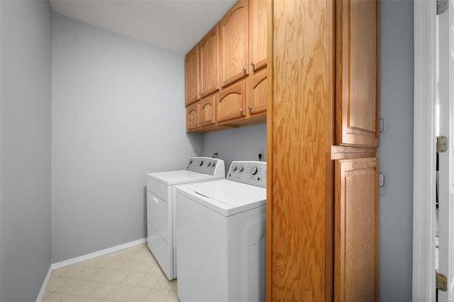 clothes washing area featuring washing machine and dryer, cabinet space, light flooring, and baseboards