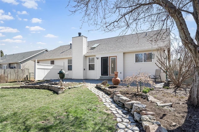 rear view of property featuring a patio, a chimney, and a shingled roof