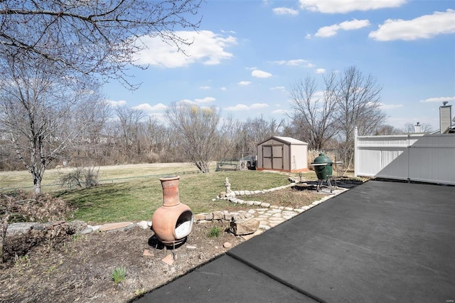 view of grassy yard with a storage shed, an outbuilding, and a patio area