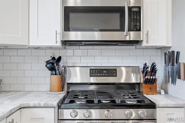 927 Gay Ave, Saint Louis, MO 63130 - kitchen featuring appliances with stainless steel finishes, white cabinets, and backsplash