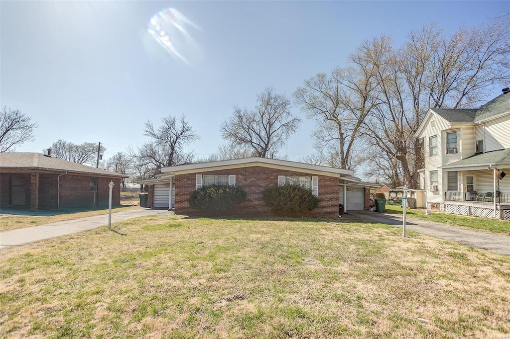 view of front facade with driveway, brick siding, an attached garage, and a front lawn