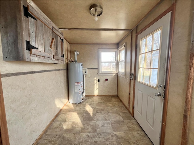 601 S Elm St, Center, MO 63436 - below grade area featuring gas water heater, baseboards, light stone finish flooring, and a textured wall