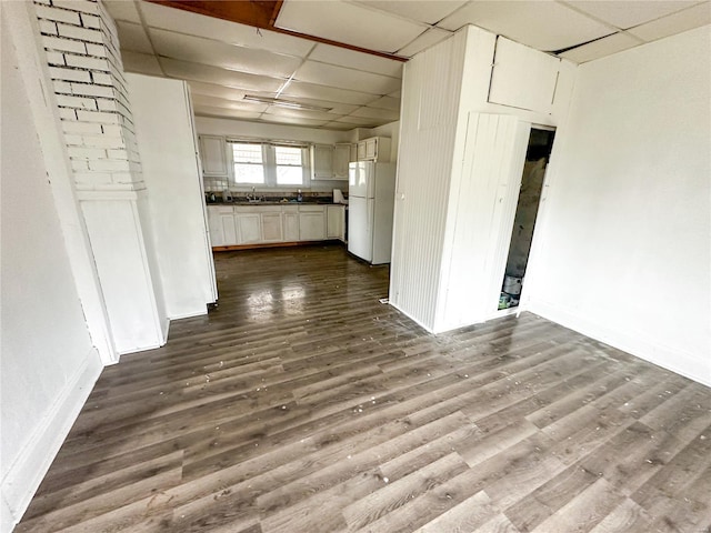 spare room with a sink, dark wood finished floors, baseboards, and a paneled ceiling