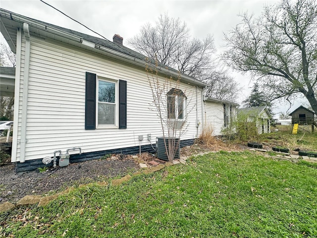 rear view of house featuring a chimney, a yard, and central air condition unit