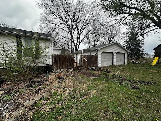 view of yard featuring fence, a garage, and an outdoor structure