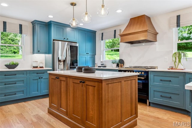 502 Briar Ridge Ln, Saint Louis, MO 63131 - kitchen featuring premium range hood, stainless steel fridge, high end range, blue cabinets, and light countertops