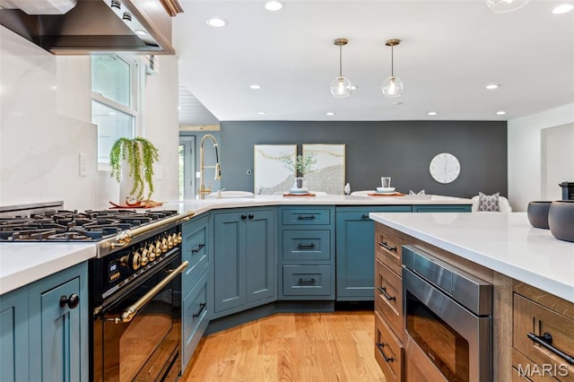 502 Briar Ridge Ln, Saint Louis, MO 63131 - kitchen featuring gas range oven, a sink, stainless steel microwave, wall chimney range hood, and light countertops