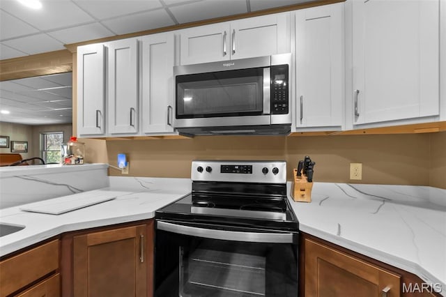 167 Red Fox Ln, Cape Girardeau, MO 63701 - kitchen featuring stainless steel microwave, range with electric stovetop, white cabinetry, light stone counters, and a paneled ceiling