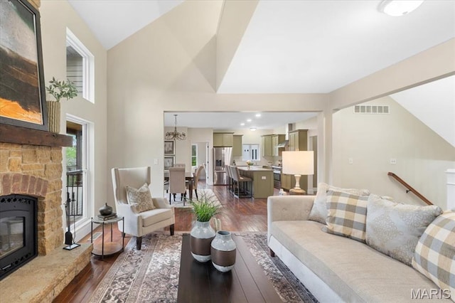 115 Place De Yeager, Lake St Louis, MO 63367 - living area with dark wood finished floors, high vaulted ceiling, a stone fireplace, and a chandelier